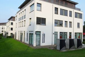 Modernes Bürogebäude mit großen Fenstern und gepflegtem Rasen im Geschäftsviertel.