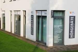 Modernes Hörgeräte-Fachgeschäft mit großer Fensterfront und gut sichtbaren Werbeschildern.